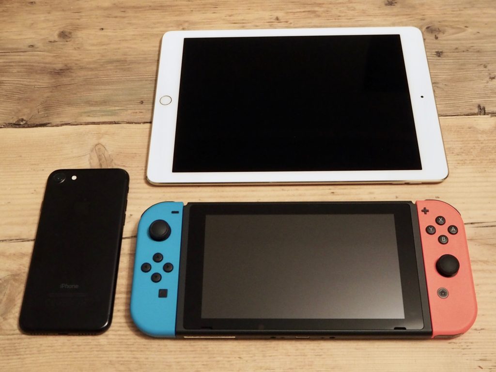 The Nintendo Switch alongside a 9.7" iPad and an iPhone 7, for size comparison.